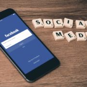 Telefon med Facebooks app på skärmen och orden "social media" i Alfapet-bokstäver